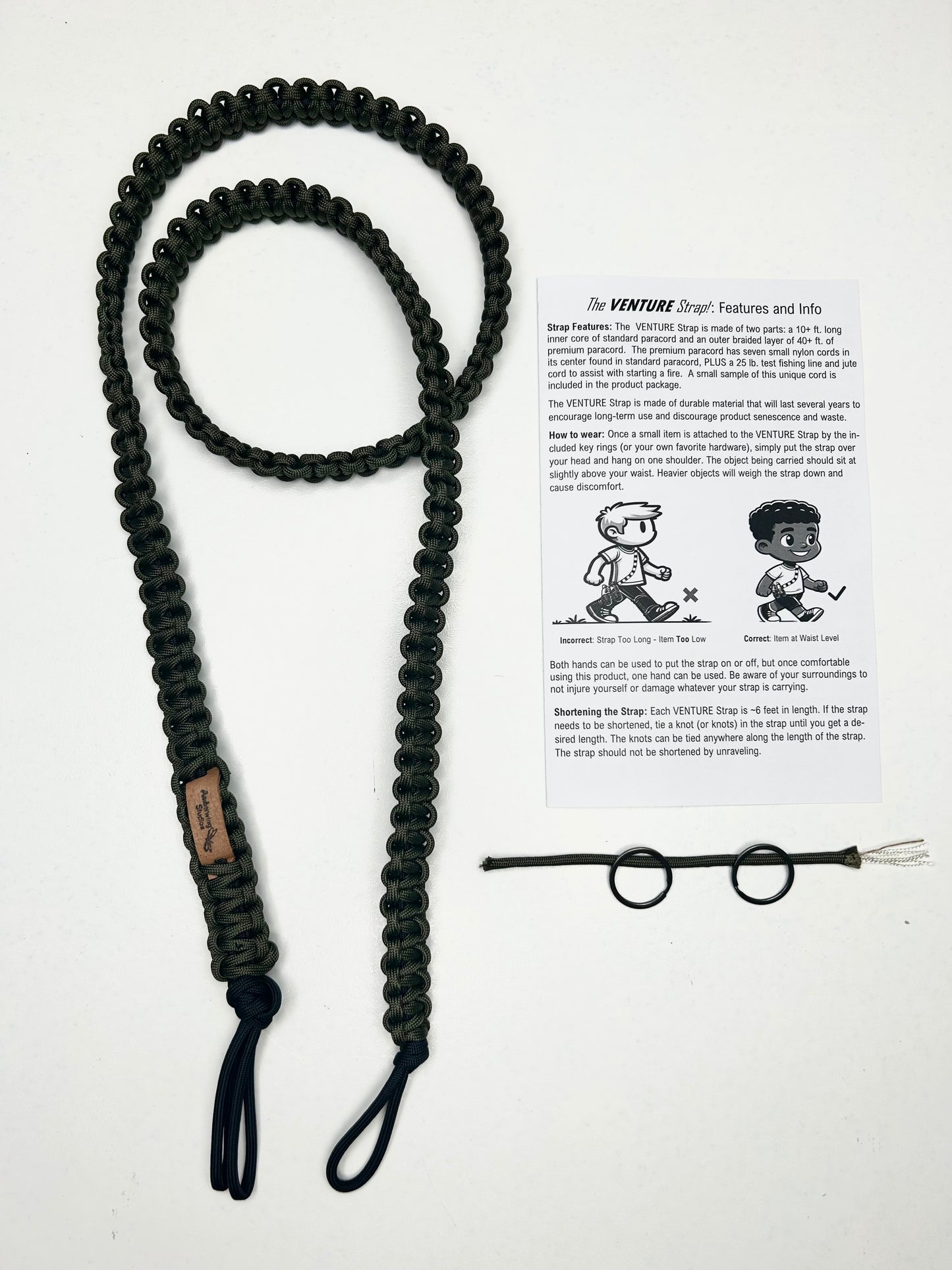 This photo features what is inside the packaging with a Venture Strap purchase. Inside the packaging is a Venture Strap, a sample of the surival paracord strap and two key rings, and a short product use and care guide. The Venture Strap is a binocular or camera strap made of sturdy paracord. The strap is worn across the body and is more comfortable and durable that traditional binocular harnesses or camera straps.